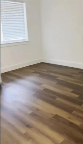 a view of a small space with wooden floor and a window
