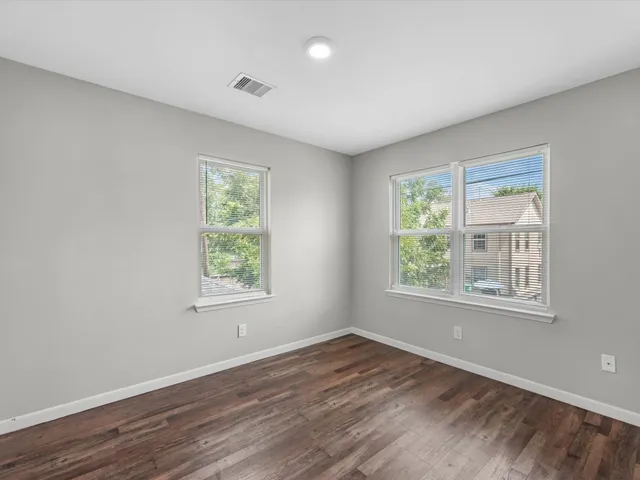 an empty room with wooden floor and windows