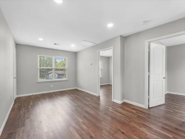 an empty room with wooden floor and window