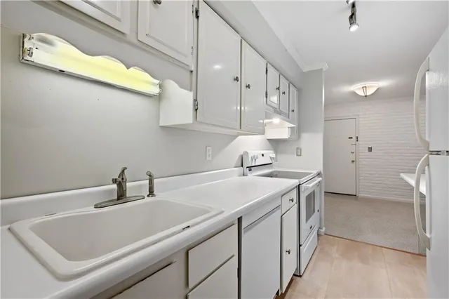 a kitchen with cabinets a sink and white appliances