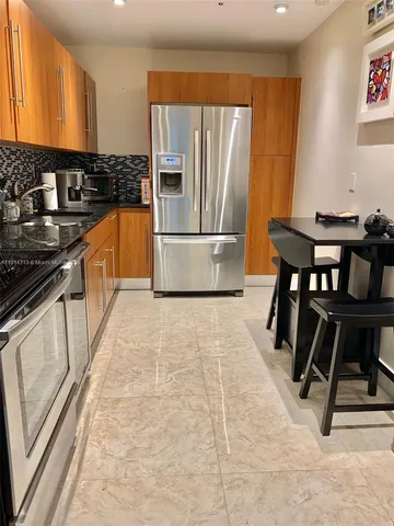 a kitchen with granite countertop a stove a sink and a refrigerator