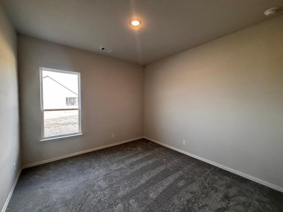 108 Pheasant Run Drive Rhome, TX 76078 - Photo 12 of 14 Recessed ceiling light fixture, neutral wall paint, white trim, grey patterned carpet, and a single-pane window
