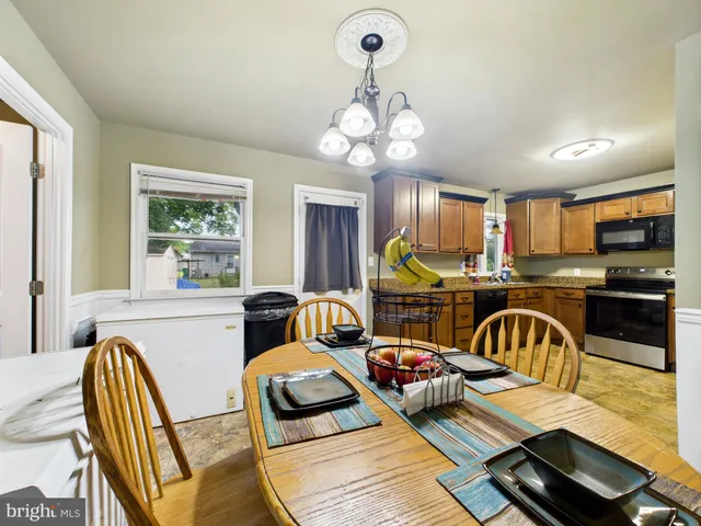 a kitchen with stainless steel appliances granite countertop a stove a sink dishwasher a dining table and chairs with wooden floor