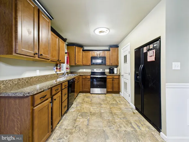 a large kitchen with granite countertop lots of counter top space and stainless steel appliances