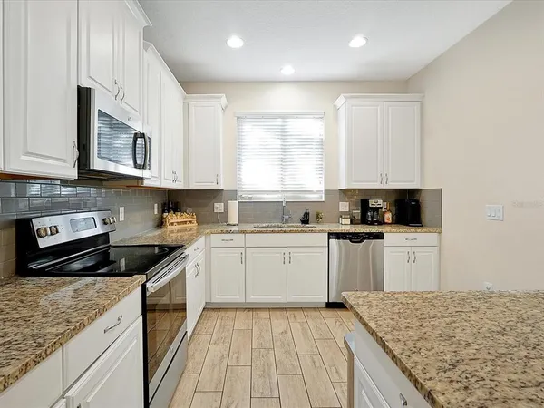 a kitchen with stainless steel appliances granite countertop a stove a sink and a microwave