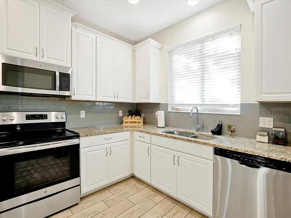 a kitchen with stainless steel appliances granite countertop white cabinets a sink and a stove