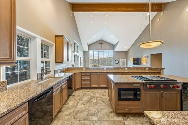 a kitchen with stainless steel appliances granite countertop a sink a stove and a refrigerator