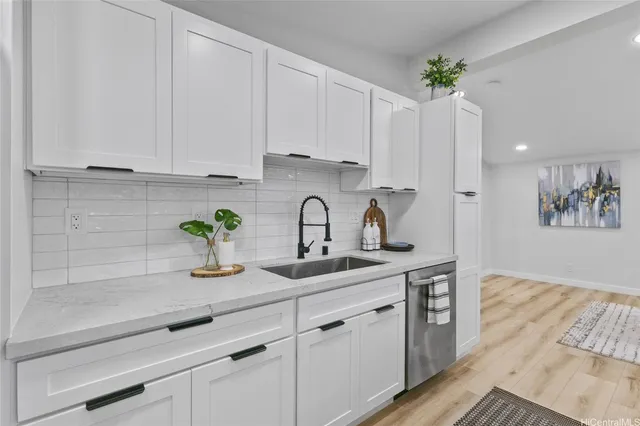 a kitchen with white cabinets a sink and dishwasher