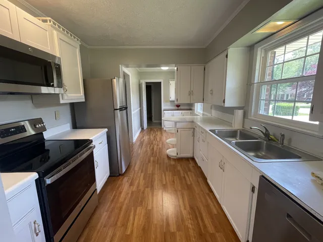 a kitchen with a sink a counter top space stainless steel appliances a window and a counter space
