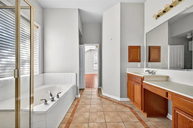 a spacious bathroom with a tub sink and mirror