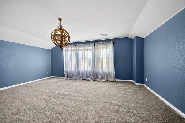 a view of an empty room with a window and chandelier fan