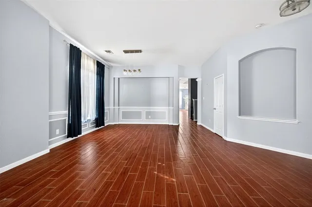 a view of an empty room with wooden floor and a window