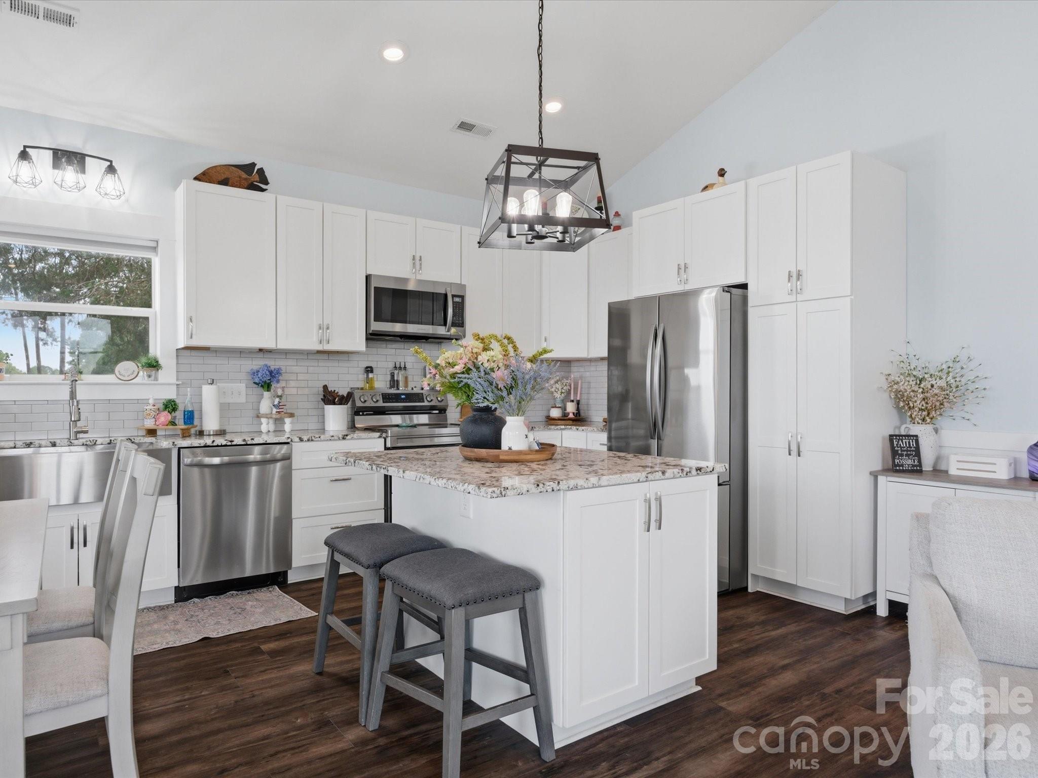 562 Lake Head Road Norwood, NC 28128 - Photo 18 of 43 a kitchen with stainless steel appliances granite countertop a refrigerator a stove a sink dishwasher a dining table and chairs with wooden floor