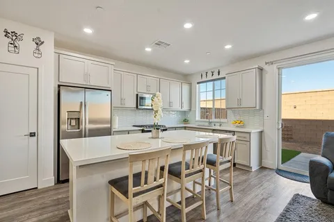 a kitchen with stainless steel appliances a table chairs refrigerator and wooden cabinets