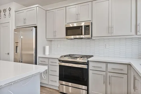 a kitchen with white cabinets and stainless steel appliances