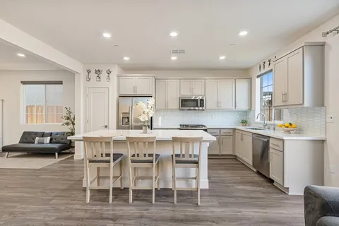 a kitchen with kitchen island granite countertop wooden floors and white cabinets