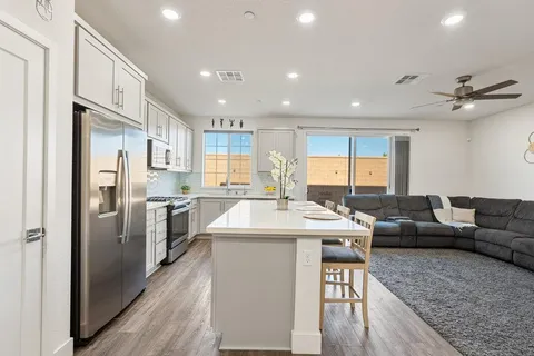 a living room with stainless steel appliances granite countertop furniture wooden floor and a view of kitchen