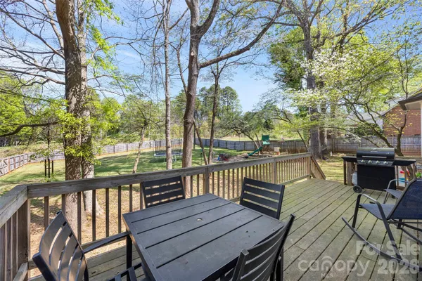 a view of a deck with chairs and large trees
