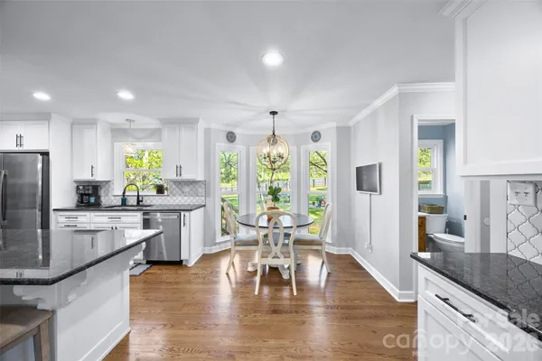 a kitchen with stainless steel appliances granite countertop a stove refrigerator and chairs