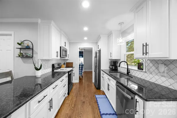 a large kitchen with stainless steel appliances granite countertop a sink stove and refrigerator