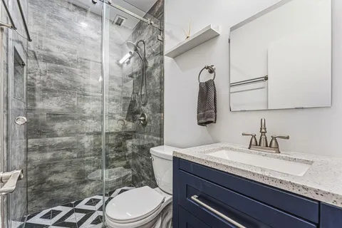 a bathroom with a granite countertop sink toilet a mirror and shower