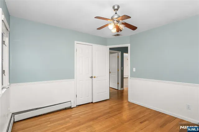 an empty room with wooden floor fan and windows