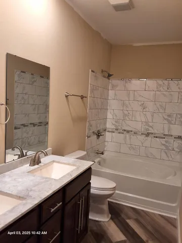 a bathroom with a granite countertop bathtub sink vanity mirror and toilet