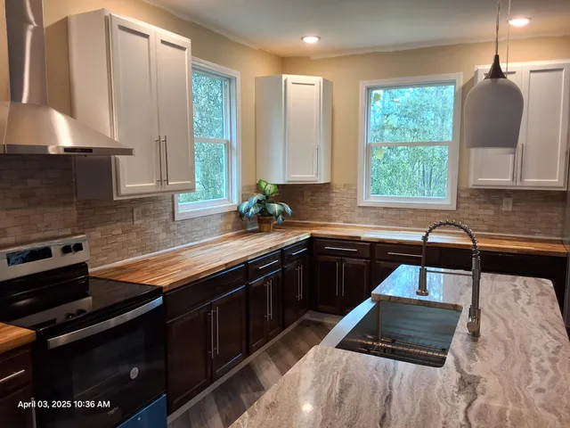 a kitchen with granite countertop a stove a sink a window and a counter top space