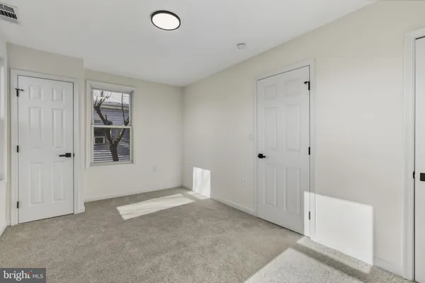 a view of an empty room with closet and a window