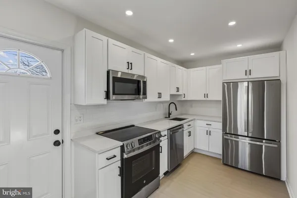 a kitchen with stainless steel appliances white cabinets and a refrigerator