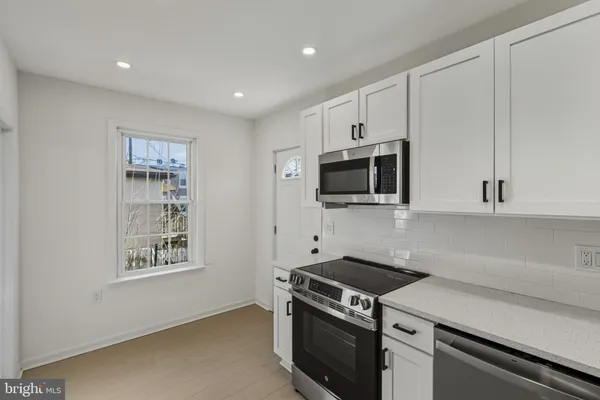 a kitchen with stainless steel appliances a stove a microwave and white cabinets