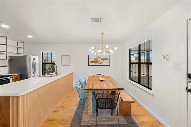 a living room with furniture a chandelier and kitchen view