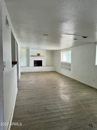 a view of a livingroom with wooden floor a fireplace and window