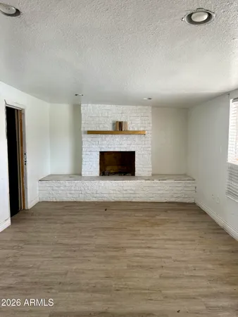 a view of empty room with wooden floor and a fireplace
