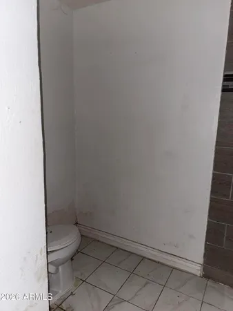 a white toilet sitting next to a white wall