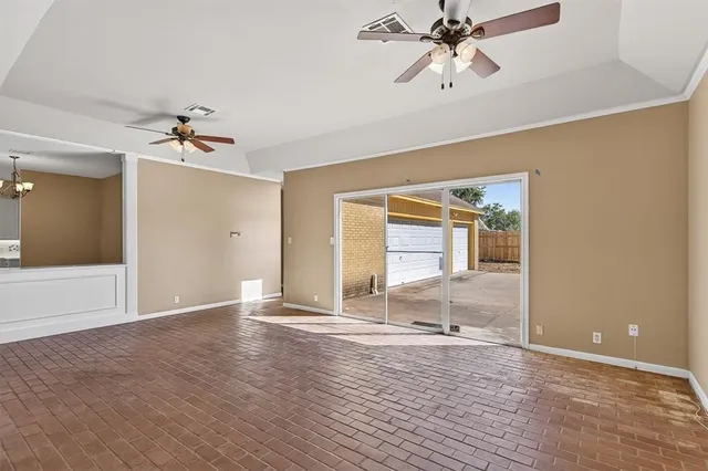 a view of an empty room with window and a ceiling fan