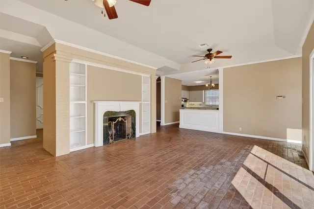a view of a livingroom with a fireplace a ceiling fan and window