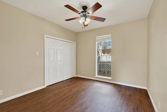 an empty room with wooden floor chandelier fan and windows
