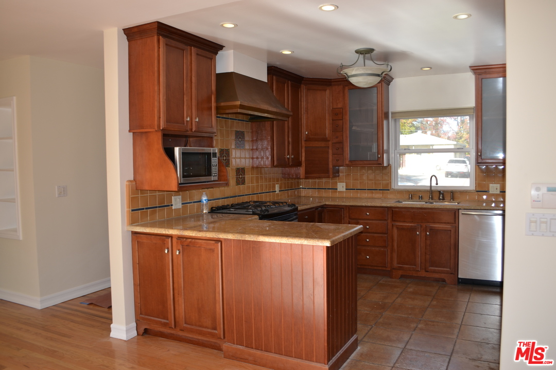 a kitchen with kitchen island granite countertop wooden cabinets and a sink
