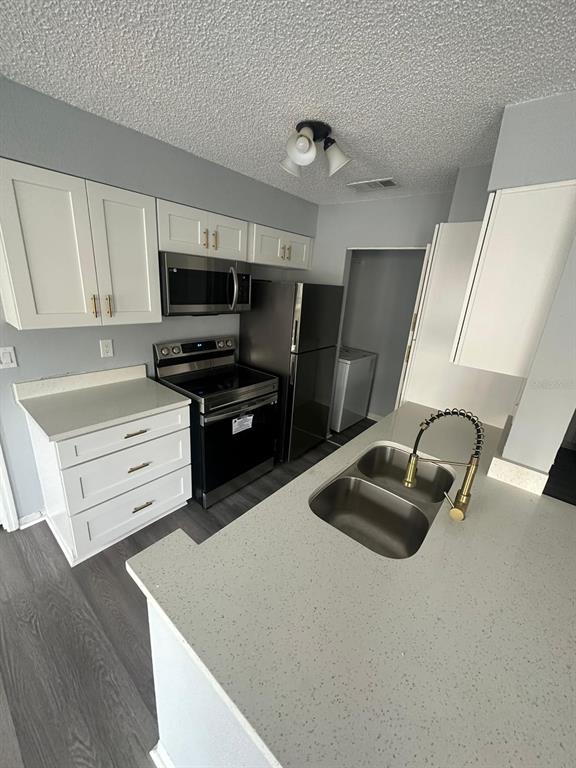 1023 South Hiawassee Road, Unit 4022 Orlando, FL 32835 - Photo 17 of 24 a kitchen with stainless steel appliances granite countertop a sink dishwasher stove and refrigerator with wooden floor