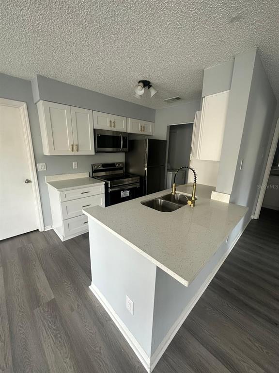 1023 South Hiawassee Road, Unit 4022 Orlando, FL 32835 - Photo 5 of 24 a kitchen with kitchen island a sink a stove a microwave and wooden floor
