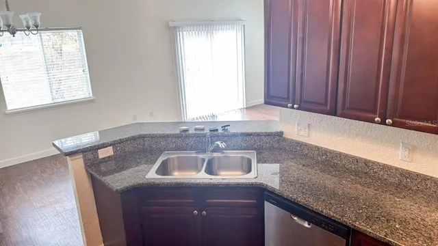 a kitchen with granite countertop a sink dishwasher window and cabinets