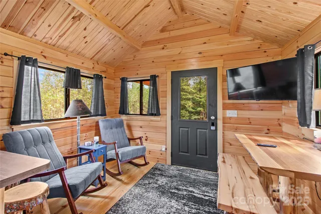 a living room with furniture a flat screen tv and floor to ceiling window