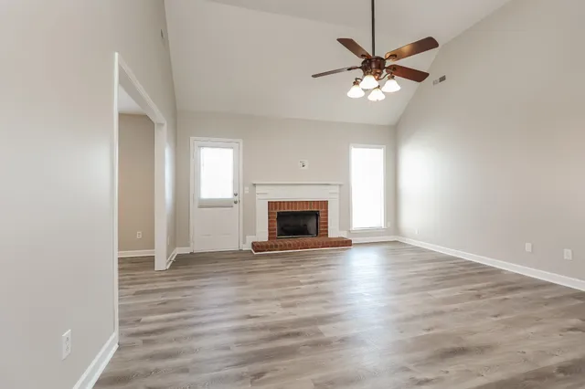 a view of a livingroom with a ceiling fan fireplace and wooden floor