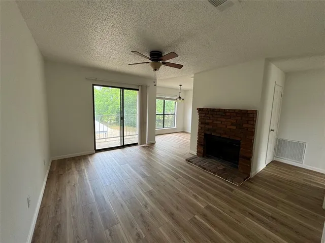 an empty room with wooden floor fireplace and windows