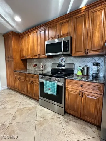 a kitchen with stainless steel appliances granite countertop a stove top oven a sink dishwasher and a microwave oven on the blue kitchen countertops