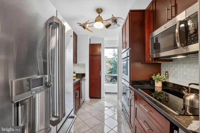 a kitchen with stainless steel appliances granite countertop a refrigerator a stove and a sink with wooden floor