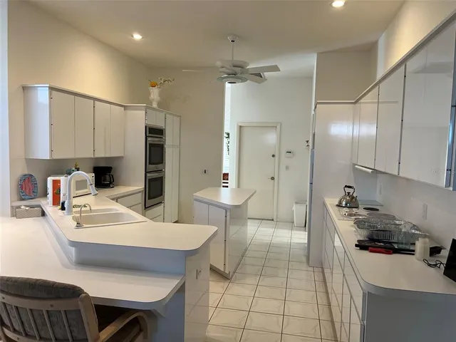 a kitchen with stainless steel appliances a sink a stove a refrigerator cabinets and dining table