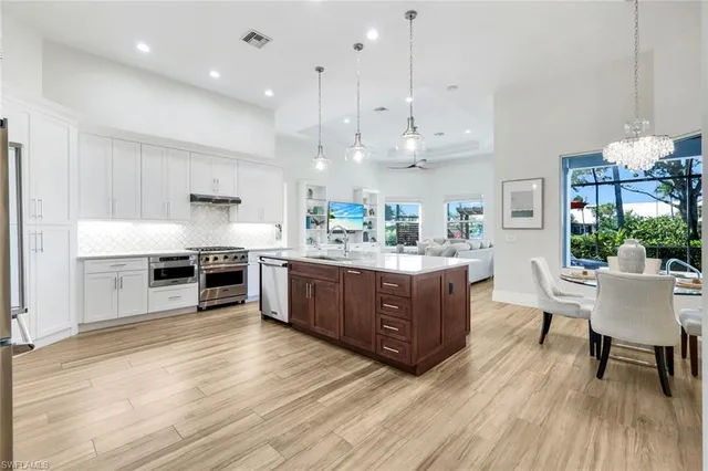 a kitchen with stainless steel appliances kitchen island granite countertop a table chairs and a wooden floors