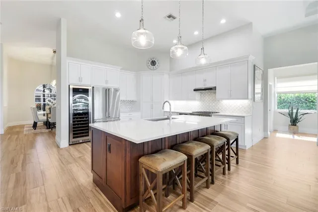 a kitchen with kitchen island granite countertop a table chairs sink and cabinets